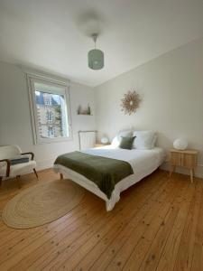 a white bedroom with a bed and a window at Villa Blanche in Agon-Coutainville