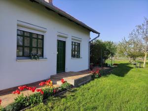 una casa blanca con flores rojas en el patio en Szőlőhegyi házikó - Cottage in the vineyard, en Balatonszemes