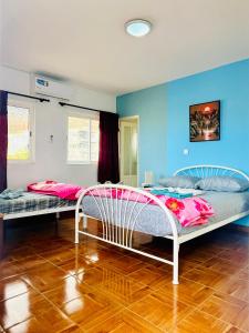 Habitación con 2 camas, paredes azules y suelo de madera. en Casa BB&Djassi en Ponta do Sol