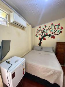 a bedroom with a bed with a tree on the wall at Hostel Sol da Barra in Salvador