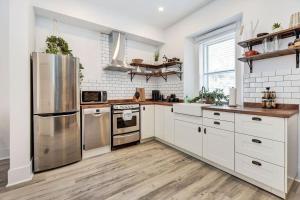 una cocina con armarios blancos y electrodomésticos de acero inoxidable en Heritage home in prime Byward Market location en Ottawa