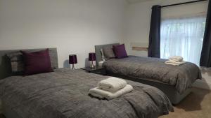 een slaapkamer met 2 bedden en handdoeken bij Ingledene in Wrexham