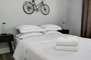 białe łóżko z rowerem wiszącym na ścianie w obiekcie High-end condo downtown Kingston near RMC Queens w mieście Kingston