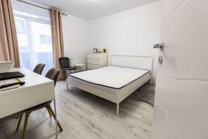 a white bedroom with a bed and a desk and a desk at West Marina Aparthotel Cluj in Floreşti