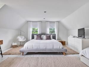 a white bedroom with a bed and a television at The Gem - Beautiful farmhouse with hot tub in West Lake