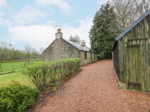 an old barn and a building with a gravel driveway at Beechgrove Cottage - Pitmedden Gardens in Ellon
