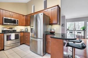a kitchen with wooden cabinets and a stainless steel refrigerator at La Hacienda - Edelweiss après-ski - wooded escape in Val des Monts