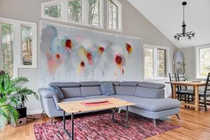 a living room with a couch and a painting on the wall at La Hacienda - Edelweiss après-ski - wooded escape in Val des Monts +48 photos