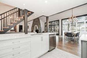 a kitchen with white cabinets and a dining room with a table at Waterfront open concept dream cottage with hot tub in Portland