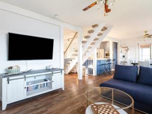 sala de estar con TV y sofá azul en Cozy family waterfront retreat recently renovated, en Deseronto