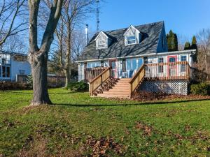 a house with a deck and a tree at Cozy family waterfront retreat recently renovated in Deseronto