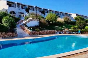 una grande piscina blu di fronte a un edificio di Mestral Apto en planta baja con piscina ad Arenal d'en Castell