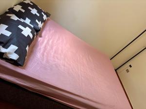 uma cama com um lençol cor-de-rosa e almofadas em Hostel do Mineiro em São José dos Campos