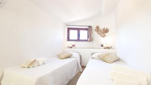 Dos camas en una habitación blanca con ventana. en Villa Sa Mama, en San Teodoro