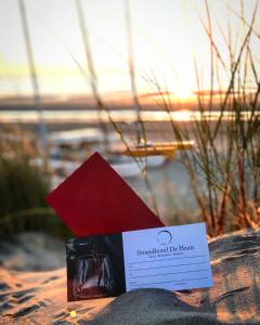 eine Flasche Wein und eine Karte am Strand in der Unterkunft Strandhotel De Haan in De Haan