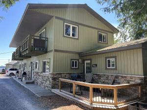 a green house with a porch and a balcony at The Picton: Beautiful Couple's Getaway in PEC in Wellington