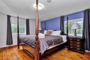a bed in a bedroom with blue walls and windows at The Highway House - PEC Waterview Getaway in Wellington
