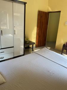 a bedroom with a white bed and a glass cabinet at Grace Air-conditioned Cool Homestay in Benaulim