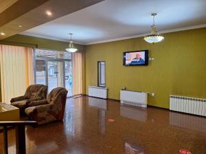 a living room with two chairs and a flat screen tv at Georgian Paradise in Kutaisi