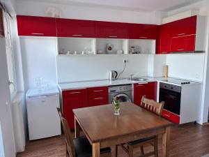 a kitchen with red cabinets and a wooden table at Квартира студия на берегу моря in Byala