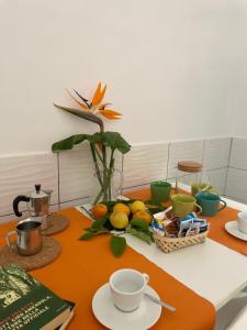 una mesa con un bol de frutas y tazas. en Tizi Apartments Porto, en Maiori