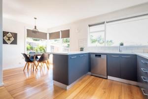 a kitchen with blue cabinets and a table with chairs at Near the CBD Perfect for Large Groups & Parking in Kings Meadows