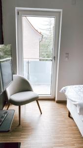 a bedroom with a chair and a bed and a window at DoreyHome P2 - modernes zentrales Apartment -2-4 Personen - Parkplatz in Passau