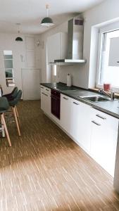a kitchen with white cabinets and a wooden floor at DoreyHome P2 - modernes zentrales Apartment -2-4 Personen - Parkplatz in Passau