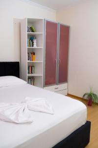 Una cama blanca en una habitación con estantería. en Albjona Guesthouse 1 en Tirana