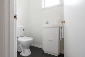 a white bathroom with a toilet and a sink at Charming Little Home Close To The City w Parking And Wifi in Kings Park