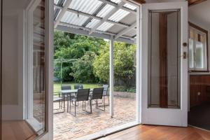 una puerta de cristal que da a un patio con mesa y sillas en Charming Little Home Close To The City w Parking And Wifi, en Kings Park