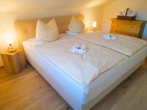 a large white bed with two flowers on it at Ferienwohnung Lorenz in Ruhpolding