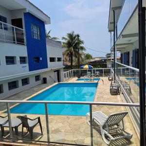 un balcón con piscina y sillas y un edificio en Recanto Do Sol Bertioga, en Bertioga