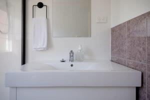 Baño blanco con lavabo y espejo en Station Cottage, en Kings Park