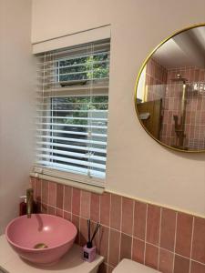 a bathroom with a pink sink and a mirror at Rosie Cottage in Ashbourne