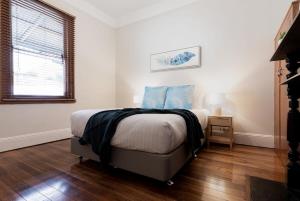 une chambre avec un lit avec des oreillers bleus dessus dans l'établissement Classic Cottage: Near CBD Hospital & Parking, à Kings Park