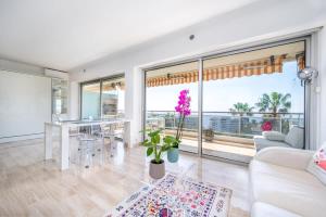 een woonkamer met een tafel en een groot raam bij Magnifique vue mer panoramique in Vallauris