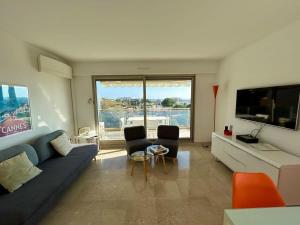 een woonkamer met een bank en stoelen en een groot raam bij A013-Apt vue mer avec piscine et terrasse in Cannes