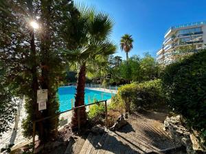 een zwembad met palmbomen en een gebouw bij A013-Apt vue mer avec piscine et terrasse in Cannes