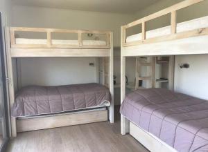 two bunk beds in a room with purple sheets at Casa Bosque Vista Hermosa al Lago Rapel in Las Cabras