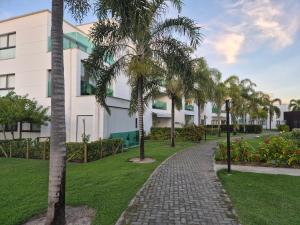 a walkway in front of a building with palm trees at Condominio Mediterraneo - Iberostate in Praia do Forte