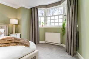 a bedroom with a bed and a window at Luxurious Park District Duplex Apartment in Glasgow