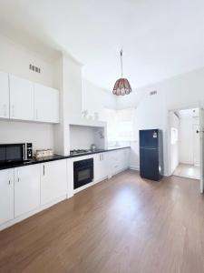 a kitchen with white cabinets and a black refrigerator at Unit In Preston For Family in Melbourne