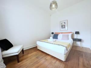 a white bedroom with a bed and a chair at Unit In Preston For Family in Melbourne