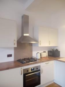uma cozinha com armários brancos e um forno com placa de fogão em Thorntree Street Edinburgh em Edimburgo