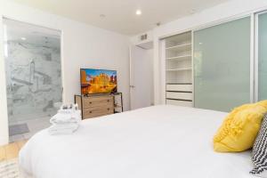 a white bedroom with a large bed and a tv at Bright and Trendy - Panoramic - Chic - Prime Location in San Diego