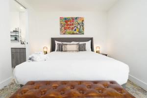 een slaapkamer met een groot wit bed met een bruine poef bij Bright and Trendy 2-story Bankers Hill Condo in San Diego