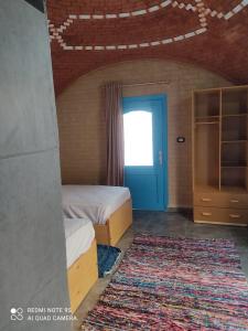 a room with two beds and a blue door at Nubian Heights in Aswan