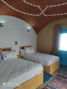 two beds in a room with a brick ceiling at Nubian Heights in Aswan