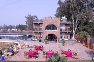 a patio with pink tables and chairs in front of a building at Ayaansh Resort- Westin Sohna Complex in Sohna